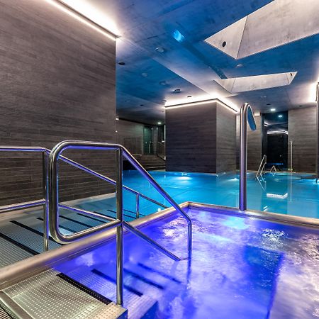Grandhotel Pupp Κάρλοβι Βάρι Εξωτερικό φωτογραφία The photo shows a modern spa area with a pool. There are sleek, dark walls and blue lighting that creates a tranquil atmosphere. A metal railing leads down into the pool, which has a section with bubbling water. The overall design features clean line
