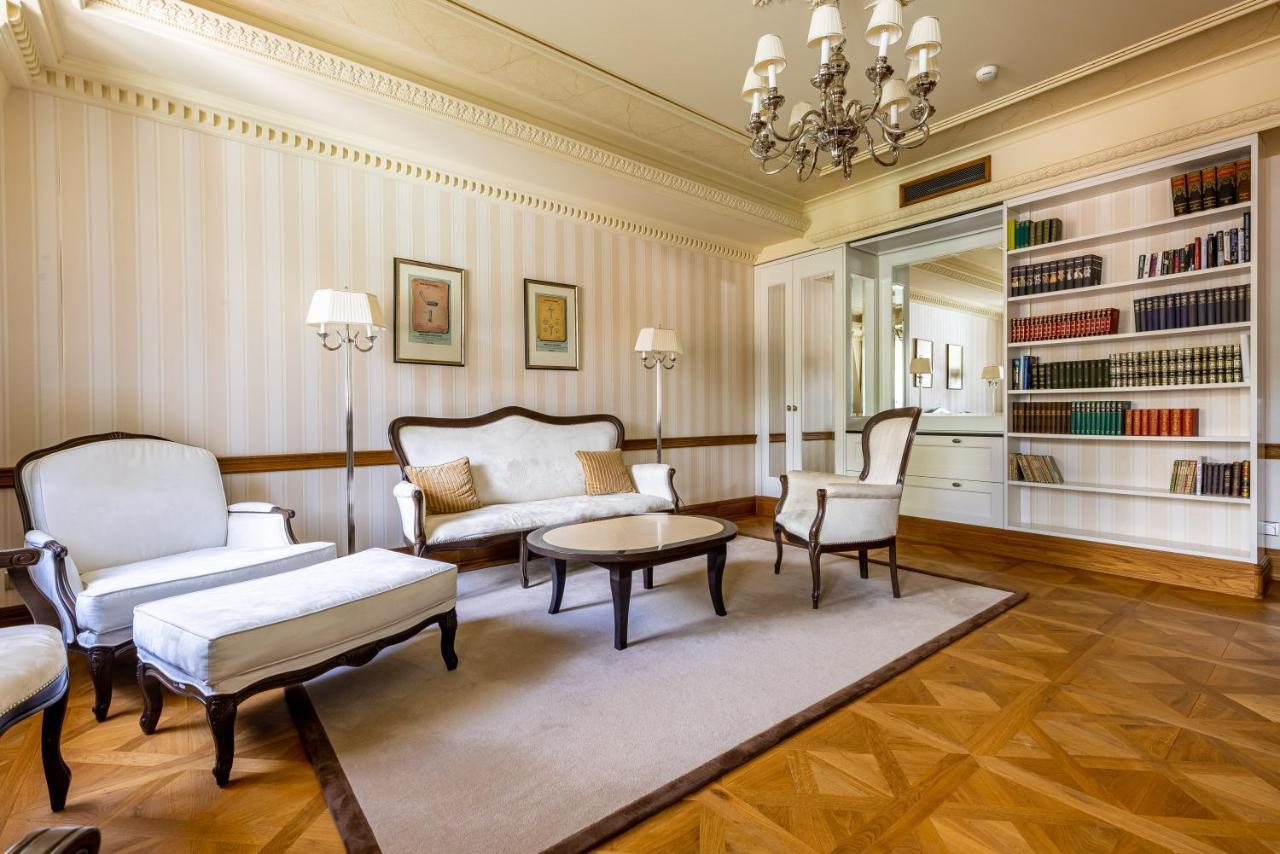 Grandhotel Pupp Κάρλοβι Βάρι Εξωτερικό φωτογραφία The photo shows a spacious and elegantly designed living room. It features a light color palette with subtle striped wallpaper. In the center, there is a round coffee table surrounded by two armchairs and a modest sofa, all in a classic style. A chan