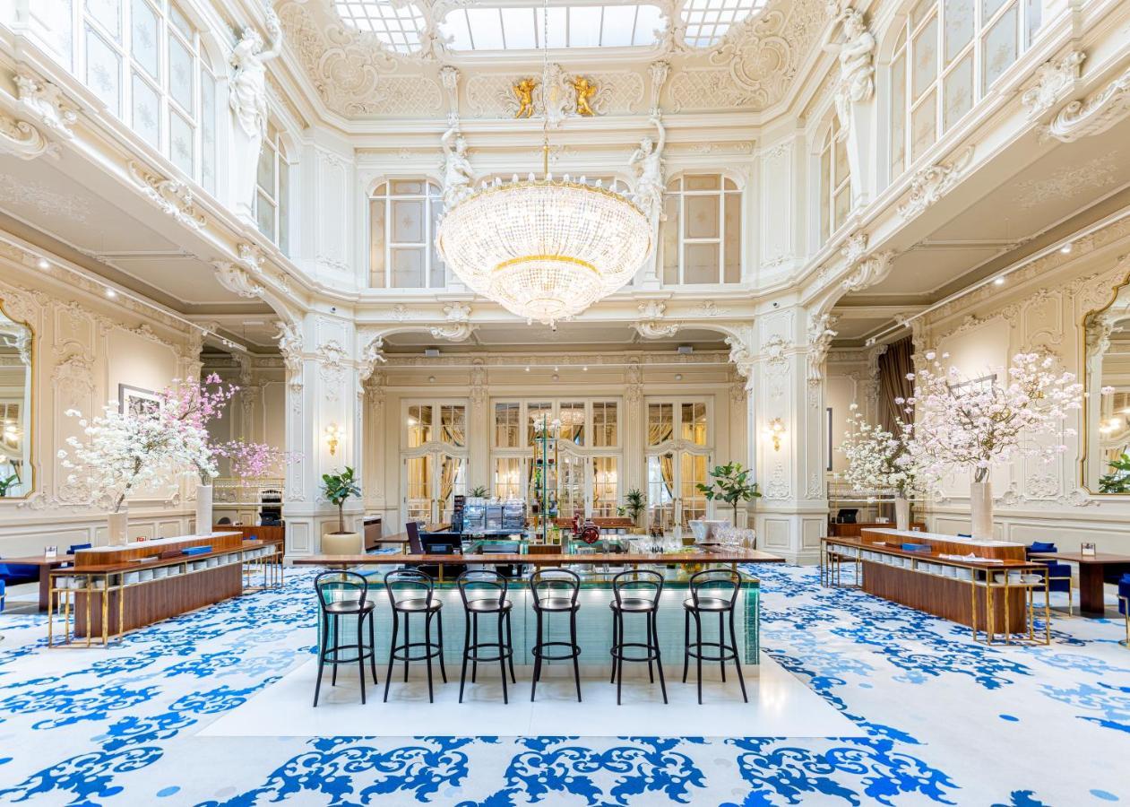 Grandhotel Pupp Κάρλοβι Βάρι Εξωτερικό φωτογραφία The photo shows an elegant interior space, likely a hotel lobby or a high-end establishment. The room features high ceilings adorned with ornate moldings and a large chandelier that hangs prominently from the ceiling. The space is filled with natural