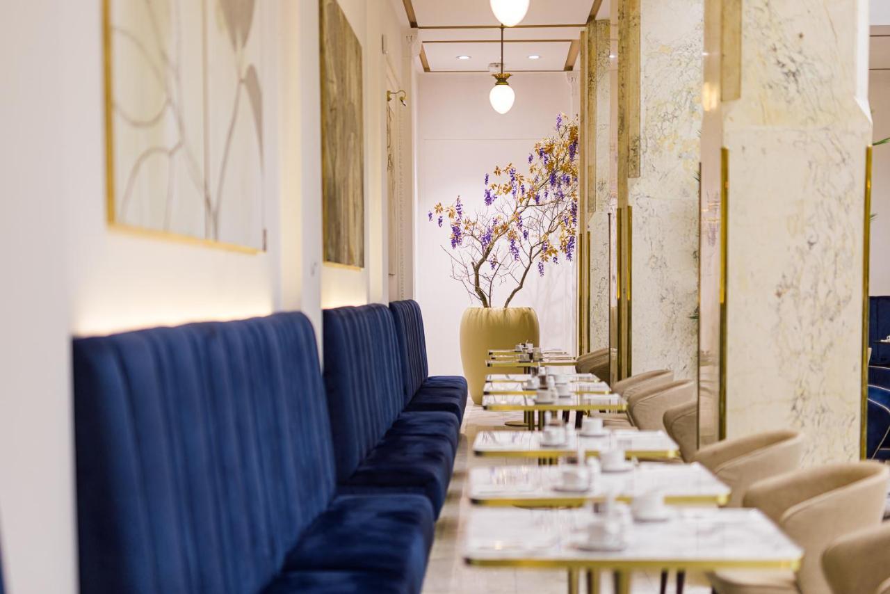 Grandhotel Pupp Κάρλοβι Βάρι Εξωτερικό φωτογραφία The photo shows a stylish and elegant interior of a café or restaurant. On one side, there are long, plush blue benches against the walls, providing seating for guests. The tables are set with white plates and cutlery, suggesting a careful arrangemen