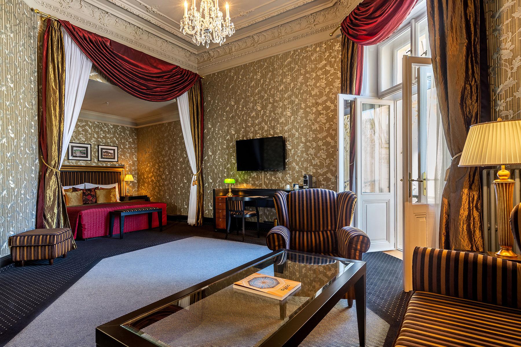 Grandhotel Pupp Κάρλοβι Βάρι Εξωτερικό φωτογραφία The photo shows a luxurious hotel room featuring elegant decor. The room has tall windows with flowing curtains, a plush carpet, and ornate wallpaper. There are two comfortable armchairs with a stylish design positioned around a glass coffee table. A