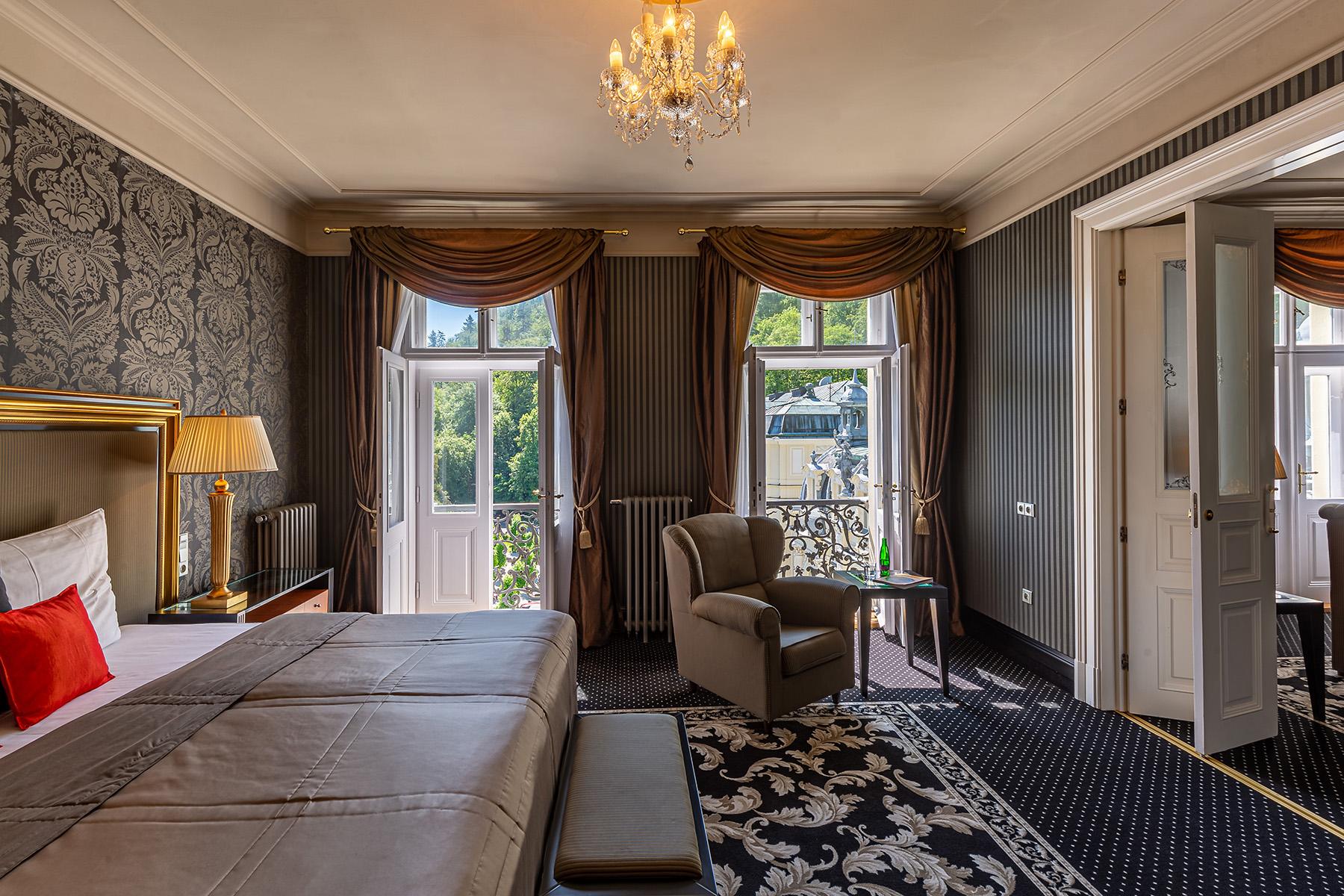 Grandhotel Pupp Κάρλοβι Βάρι Εξωτερικό φωτογραφία The photo shows a beautifully decorated hotel room or suite. It features a large bed with a stylish headboard and luxurious bedding. The walls are adorned with elegant wallpaper, and there are draped curtains framing two large windows that let in nat