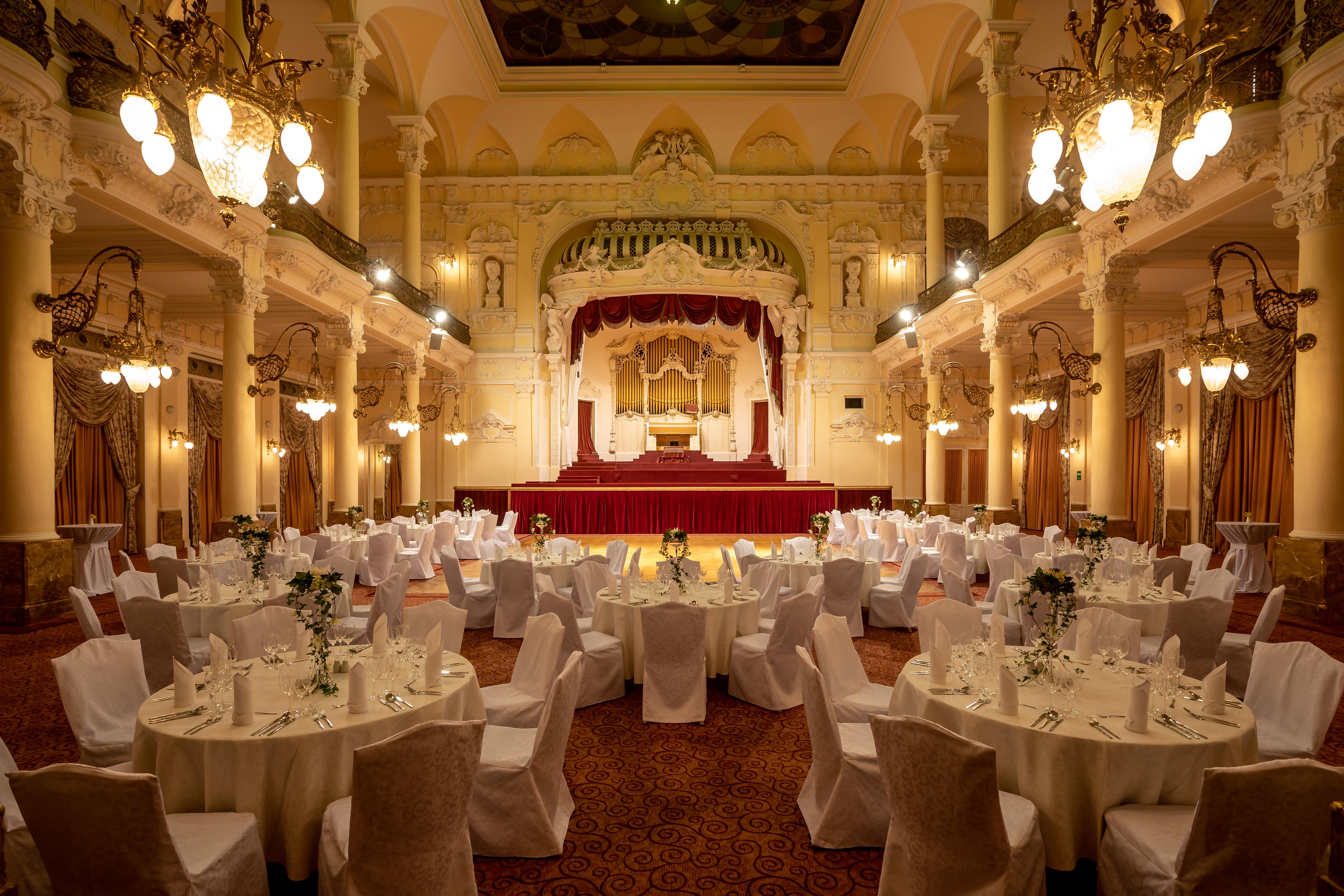 Grandhotel Pupp Κάρλοβι Βάρι Εξωτερικό φωτογραφία The photo depicts an elegantly decorated banquet hall. The room features several round tables, each covered with white tablecloths and adorned with floral arrangements. Surrounding the tables are chairs, also draped in white fabric. 

The venue is ch