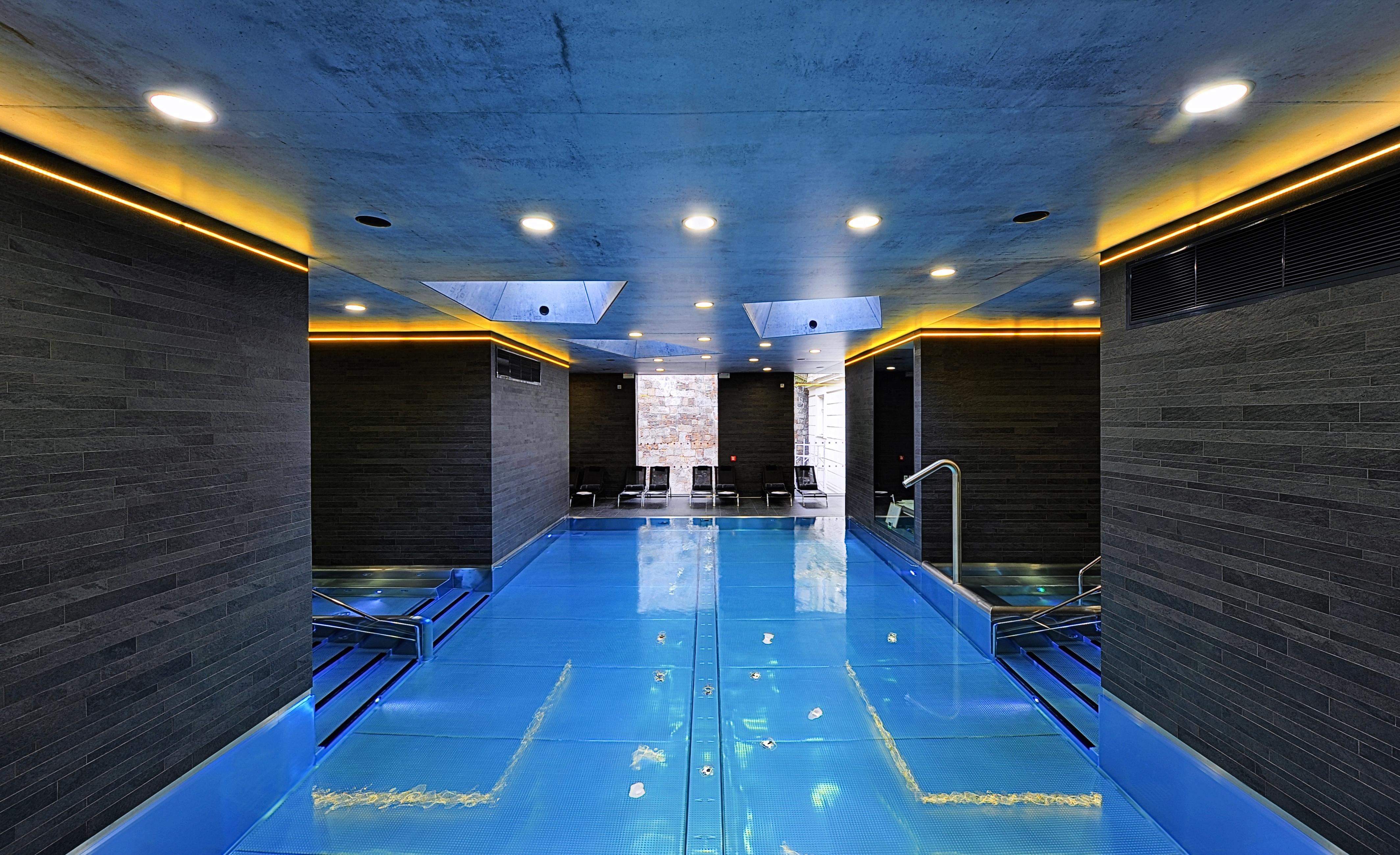 Grandhotel Pupp Κάρλοβι Βάρι Εξωτερικό φωτογραφία The photo shows a modern indoor swimming pool area. The pool features a striking blue surface and is surrounded by sleek, dark walls. Ambient lighting, including soft yellow or warm lights along the edges, enhances the contemporary aesthetic. There a