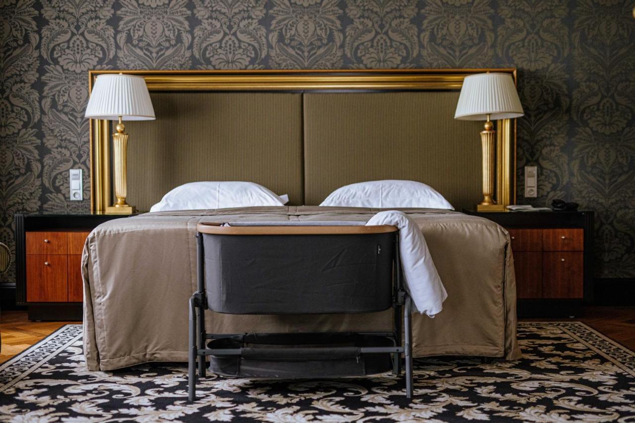 Grandhotel Pupp Κάρλοβι Βάρι Εξωτερικό φωτογραφία The photo shows a cozy hotel room with a stylish design. In the center, there are two beds with white pillows and a beige bedspread. Flanking the beds are two elegant lamps on side tables, and behind the beds is a large gold-framed headboard. At the 