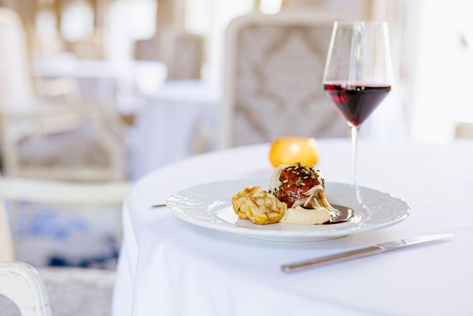 Grandhotel Pupp Κάρλοβι Βάρι Εξωτερικό φωτογραφία The photo shows a beautifully arranged dining table setting. On the table, there is a white plate containing two food items: one appears to be a meatball or similar dish, and the other looks like a golden-brown pastry or fritter. Accompanying the dis