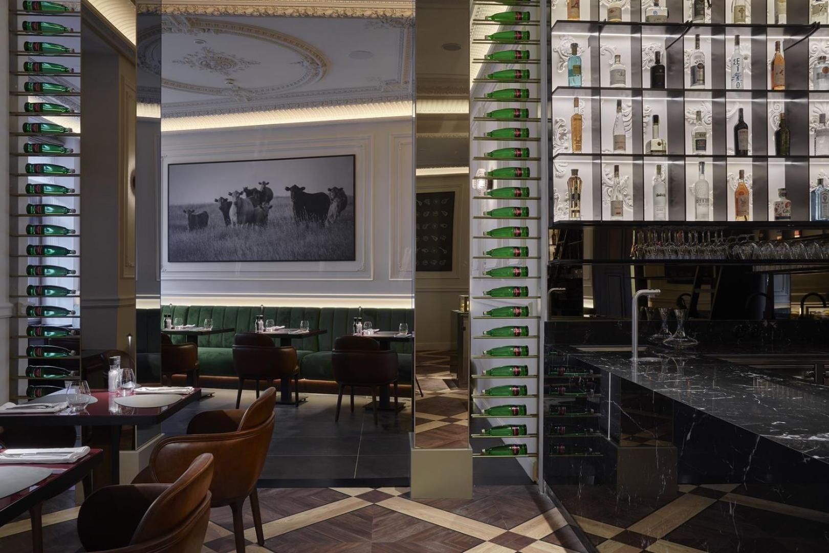 Grandhotel Pupp Κάρλοβι Βάρι Εξωτερικό φωτογραφία The photo shows the interior of a stylish restaurant. There is a large photograph of cows on the wall, adding a rustic touch to the decor. The space features elegant seating with dark brown chairs, and the tables are set for dining. A bar area is vis