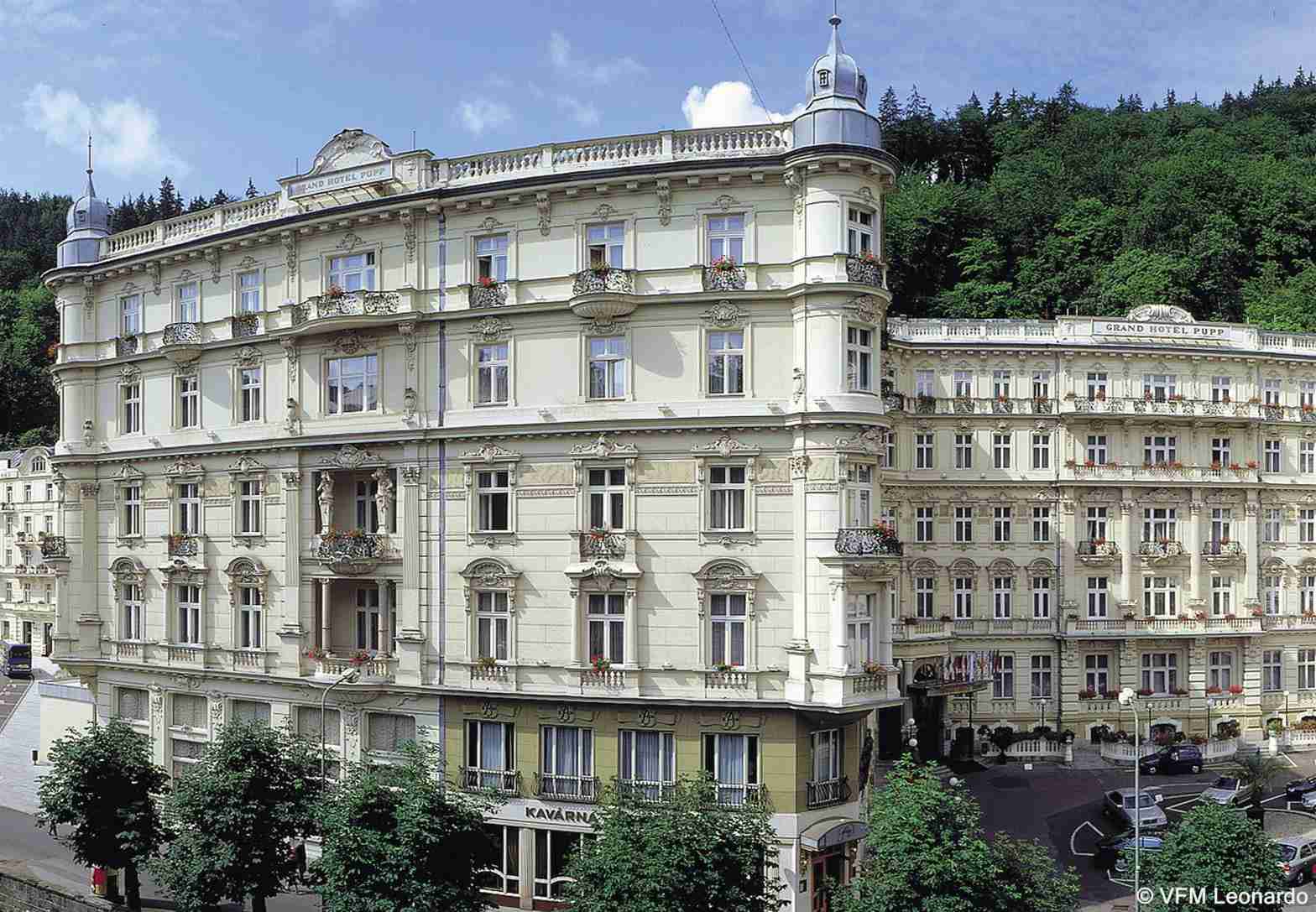 Grandhotel Pupp Κάρλοβι Βάρι Εξωτερικό φωτογραφία The photo shows a beautiful architectural scene featuring two elegant buildings. The structures exhibit a classic design with intricate details, large windows, and ornate balconies. They are painted in a light color, possibly cream or pale yellow, wh