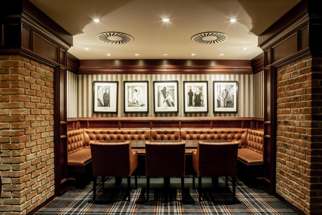 Grandhotel Pupp Κάρλοβι Βάρι Εξωτερικό φωτογραφία The photo shows an elegantly designed room, likely a private dining or meeting area. It features a circular seating arrangement with a table surrounded by plush, brown leather chairs. The walls are adorned with a combination of exposed brick and stri